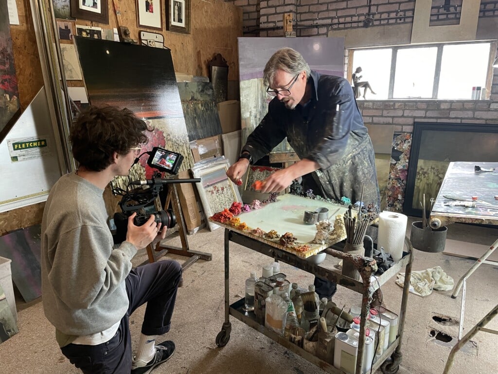 Cameraman filming a close up of an artist at work