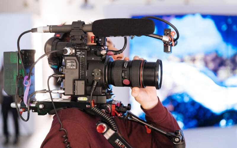 Side view of a man holding a video camera on his shoulder