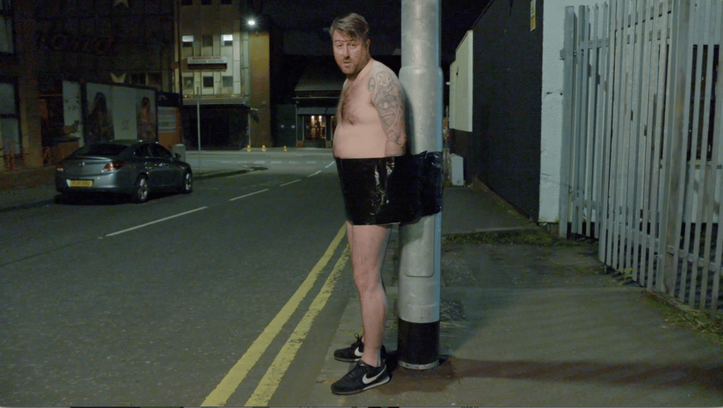 Nude man duct taped to a telephone pole at night whilst on a stag do