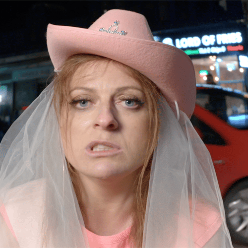 Blonde woman in a pink bridal cowboy hat making faces at the camera