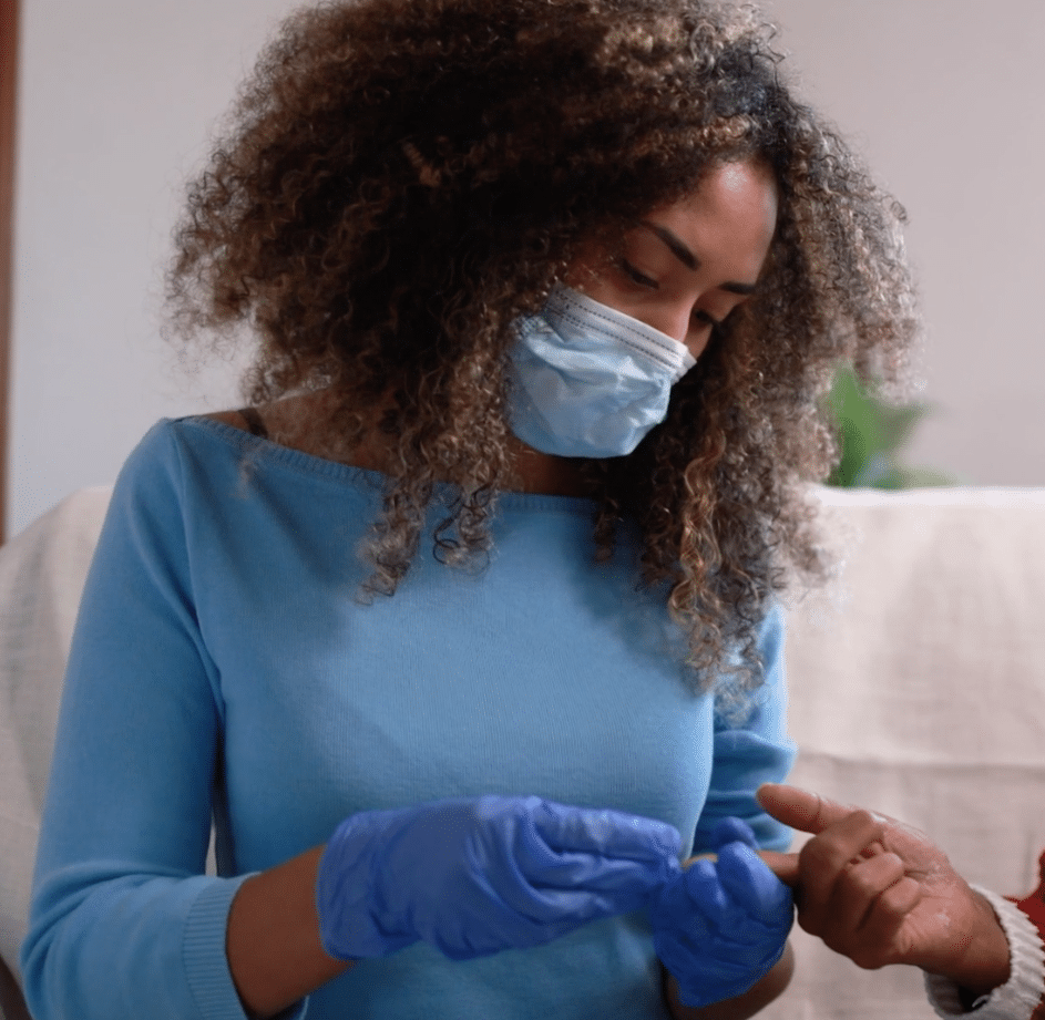 Woman in a mask and medical gloves holding the finger of someone off camera