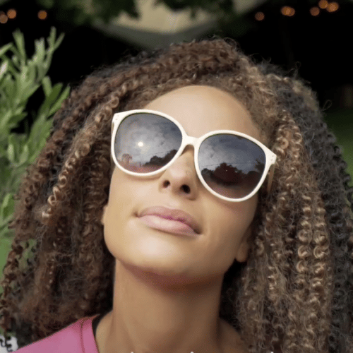 Woman wearing large white sunglasses and looking at the sky