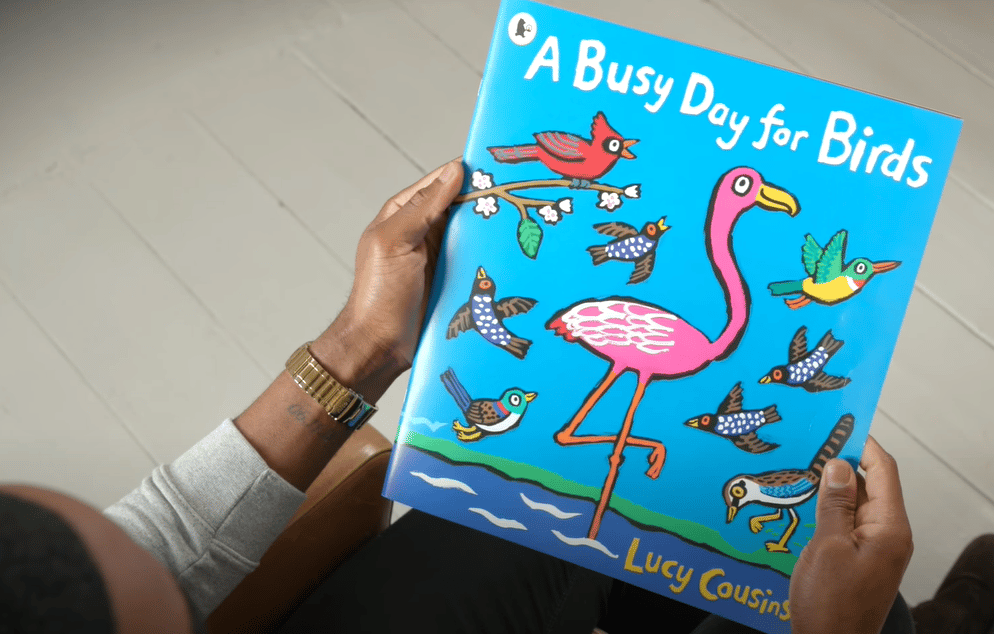 Hands holding a copy of A Busy Day For Birds by Lucy Cousins