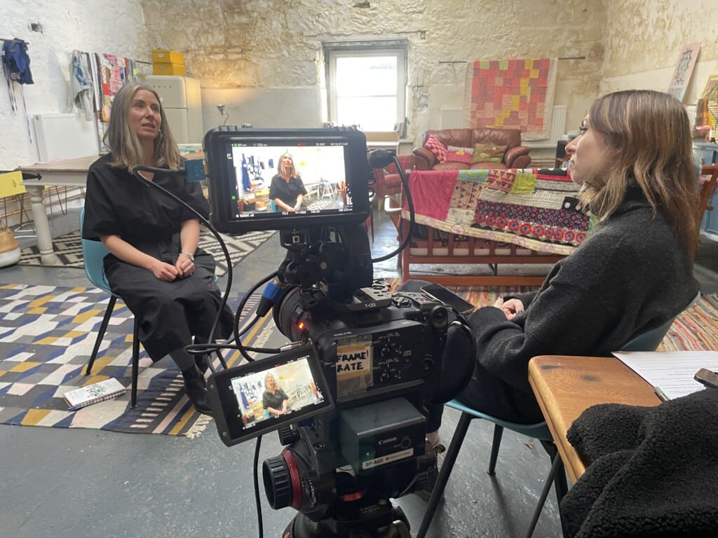 A woman is interviewed by another woman while being filmed